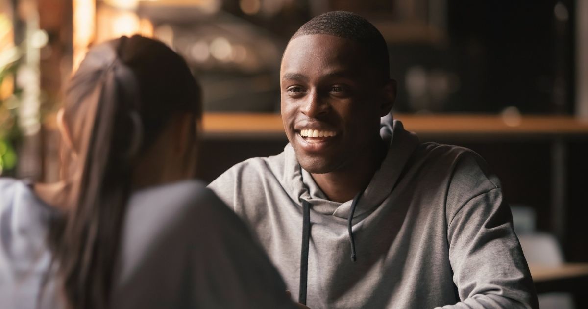 A man smiling as he talks to a woman at a local speed dating event.
