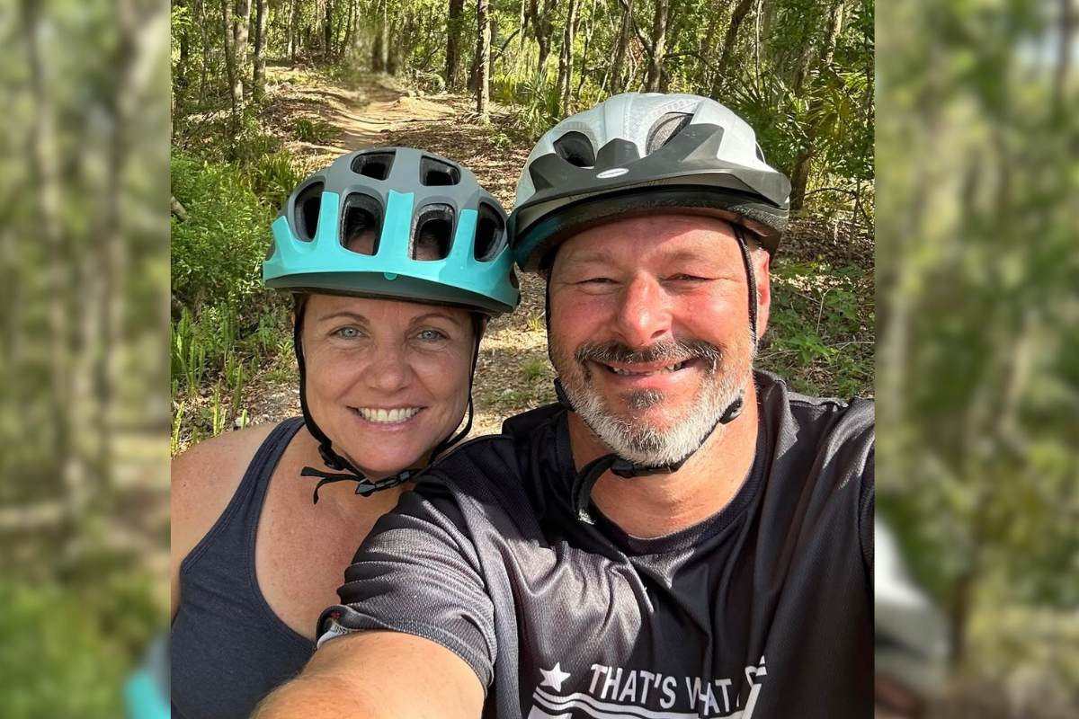 Eddie and Heather on a bike ride. They are wearing helmets and smiling.