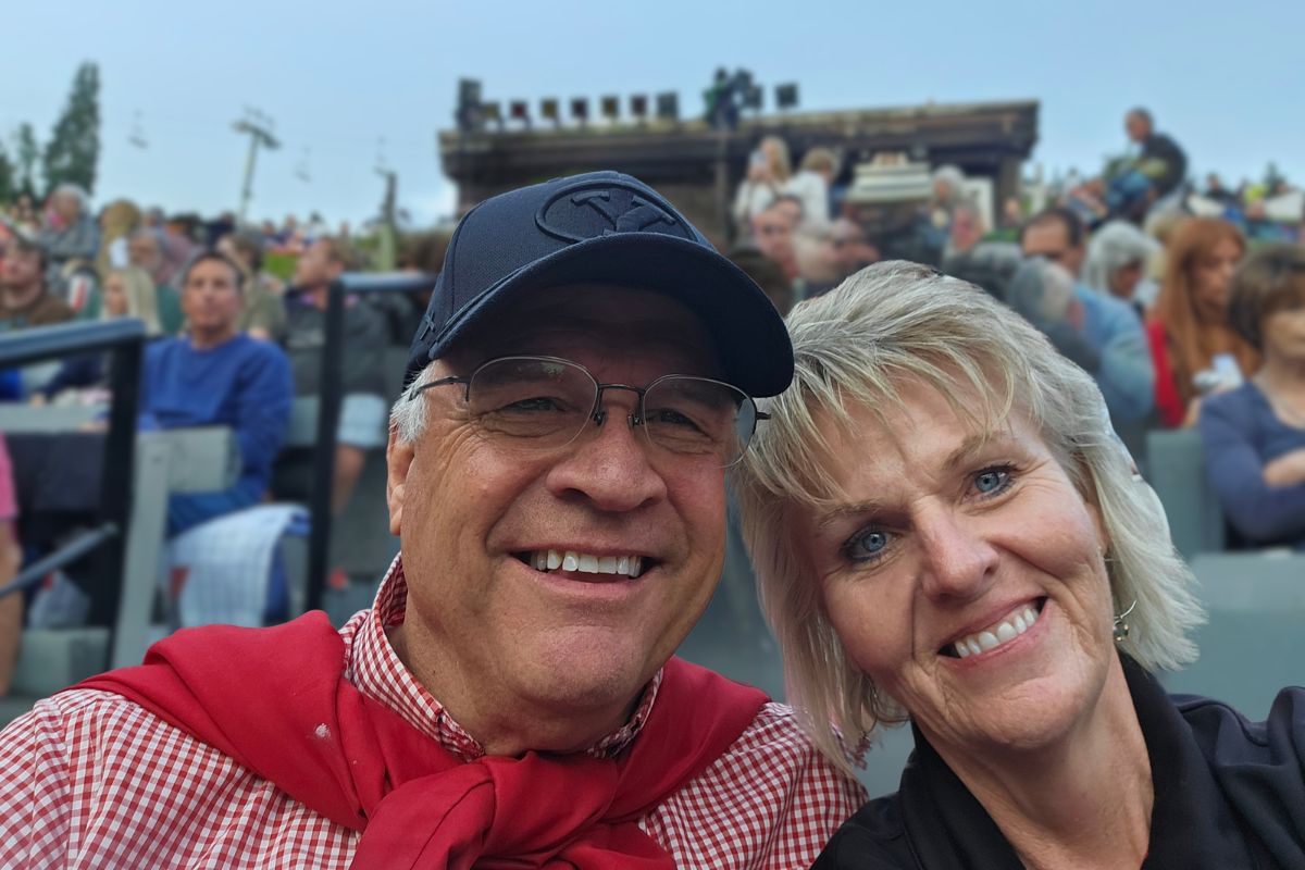 Daniel and Carolyn smiling in a casual selfie taken at a sporting event.