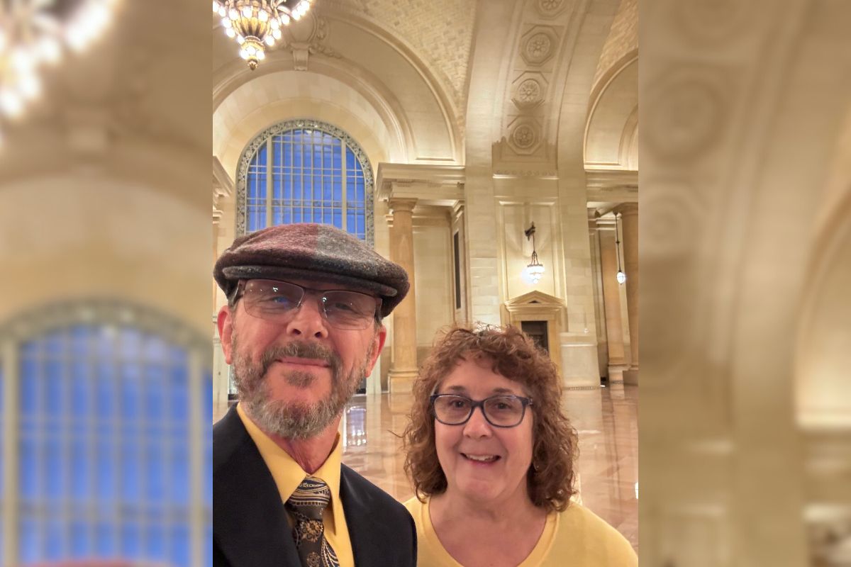 Steven and Diane on a date, smiling in a selfie. They are nicely dressed and standing in a beautiful room.