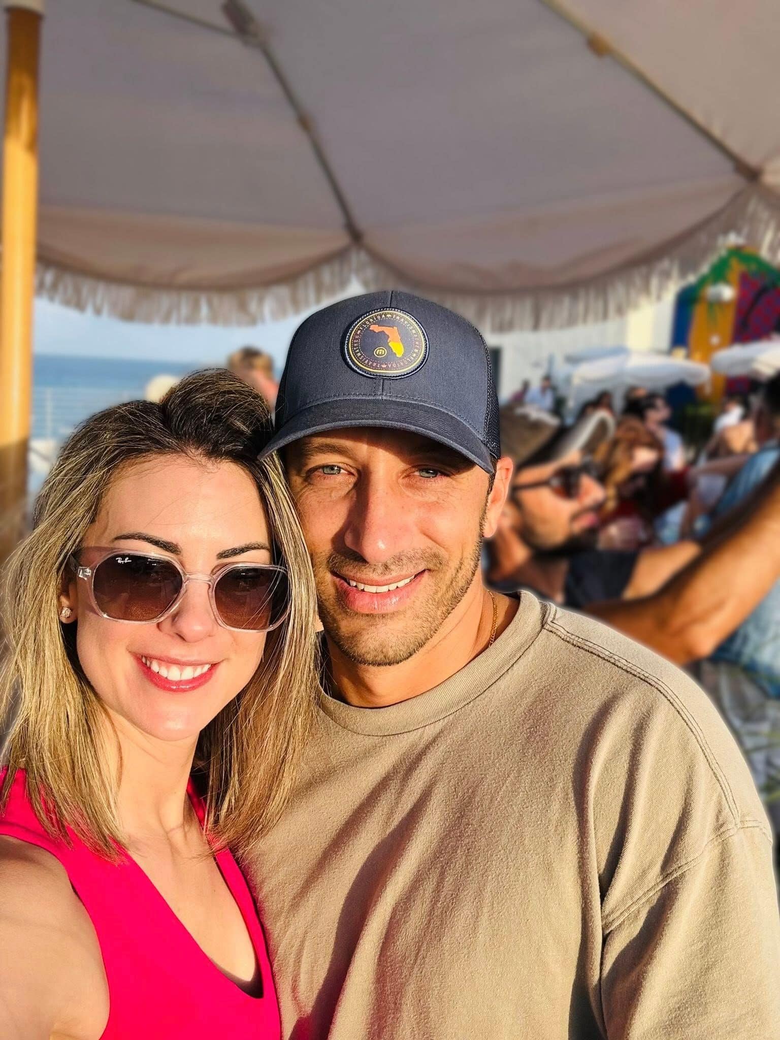 Frank and Niki posing for a casual selfie under a sun umbrella.
